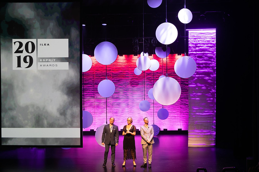 Three presenters on a stage presenting award content